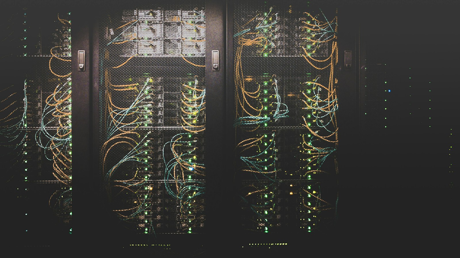 Rows of server racks with colorful cables in a dark data center